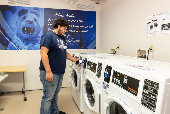 student using phone to pay for laundry with his mobile id+ card